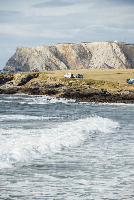 Vista sull'oceano ondulato e le auto parcheggiate sul prato al mare. — Foto stock
