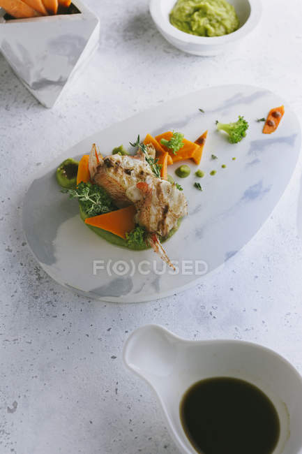 Риба на грилі з горошком і морквяними паличками на мармуровій тарілці — стокове фото