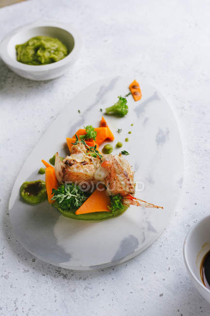 Grilled scorpion fish with mashed peas and carrot sticks on marble plate — Stock Photo