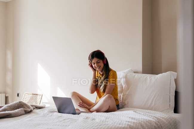 Mulher em fones de ouvido usando laptop — Fotografia de Stock