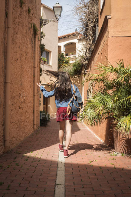 Chica con mochila caminando en la calle - foto de stock