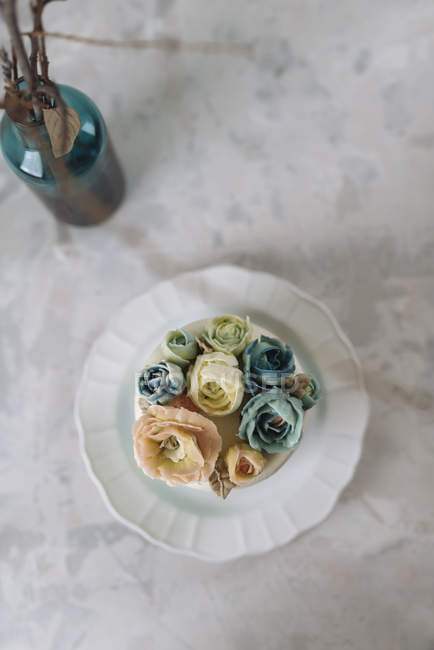 Wedding cake with blue and beige buttercream flowers on white plate — Stock Photo