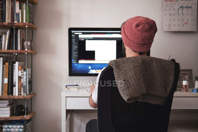 Back view of freelancer man sitting at workplace and using stationery computer in Munich — Stock Photo