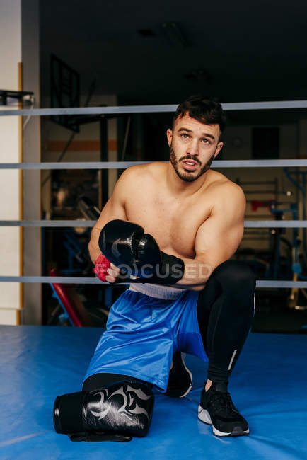 Homem sentado de joelhos no ringue de boxe — Fotografia de Stock