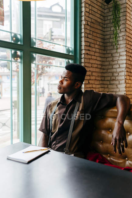 Чернокожий мужчина сидит за столом в кафе — стоковое фото
