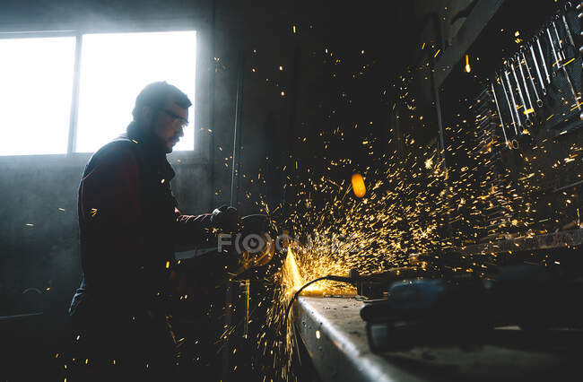 L'homme travaille avec meuleuse coupe métal. — Photo de stock