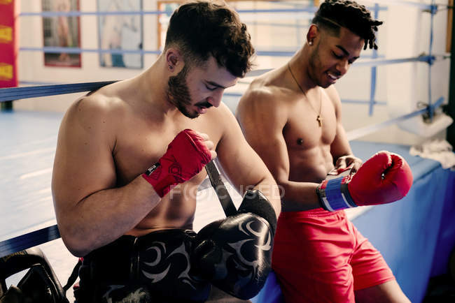 Muscular men putting on boxing gloves — Stock Photo
