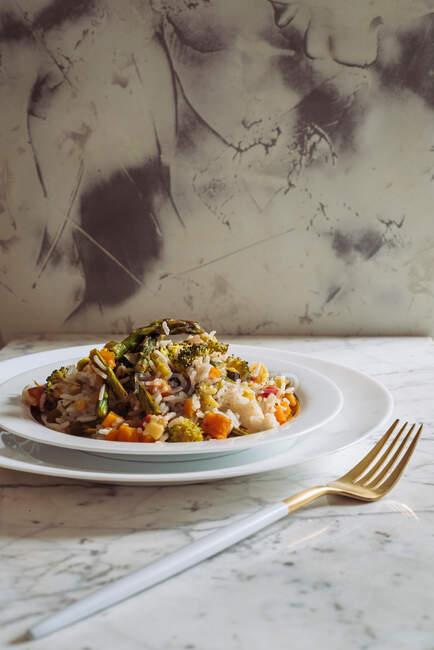 Рис басмати с овощами из соуса, на белом мраморном столе — стоковое фото