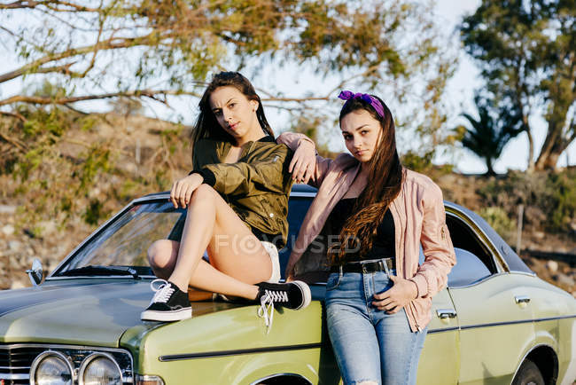 Women posing at green car — Stock Photo