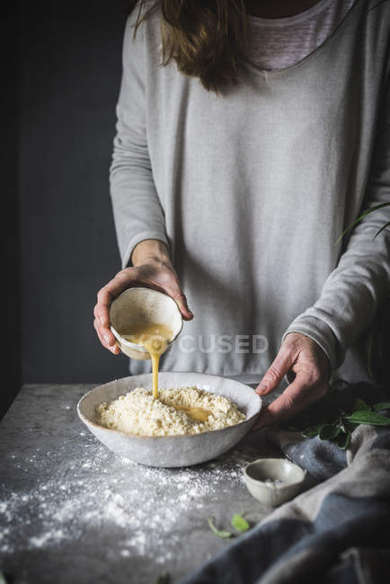Woman pouring egg into dough — Stock Photo