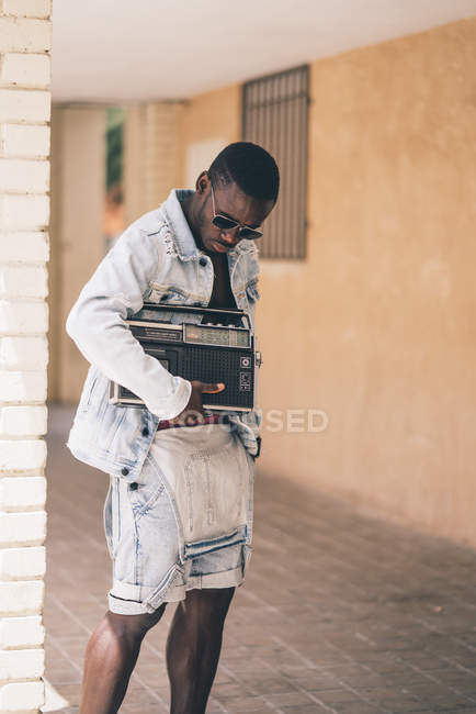 Black man in sunglasses holding vintage radio device outdoors — Stock Photo
