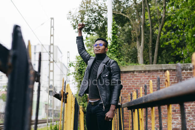 Чернокожий мужчина стоит на улице с поднятой рукой — стоковое фото