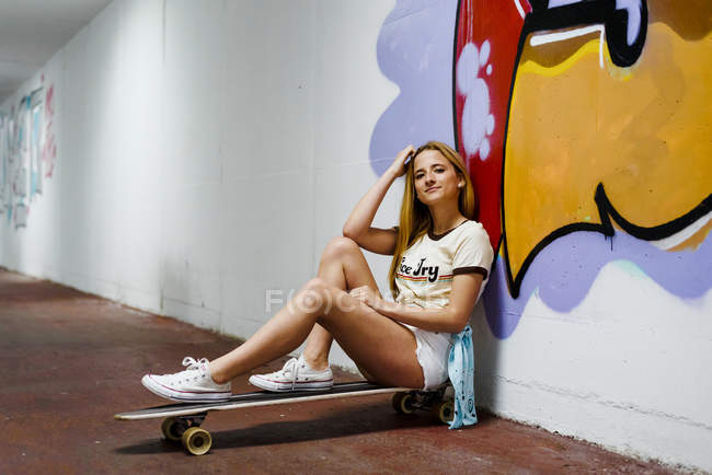 Blond girl sitting on longboard — Stock Photo