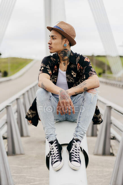 Hipster sitzt auf Brückengeländer — Stockfoto