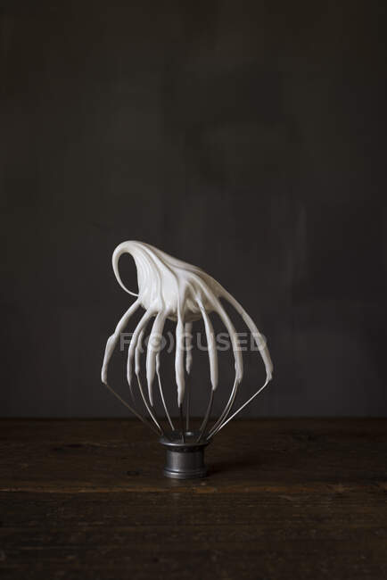 Meringue on a whipper on black background — Stock Photo