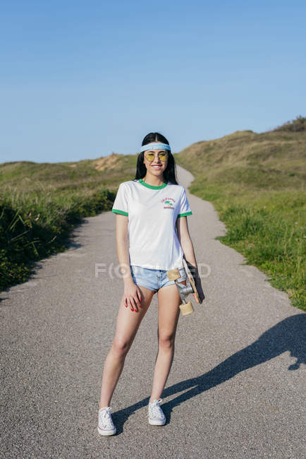 Menina com longboard de pé na estrada — Fotografia de Stock