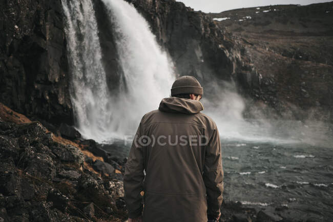 Touriste avec caméra debout à la cascade — Photo de stock