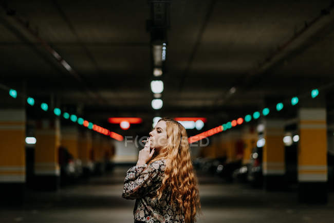 Pretty redhead woman smoking on parking lot — Stock Photo