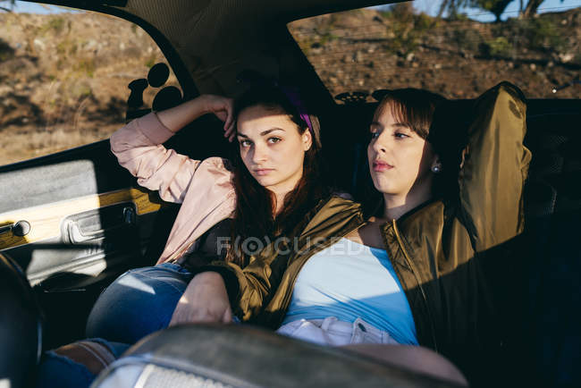 Mujeres sentadas en el asiento trasero en el coche - foto de stock