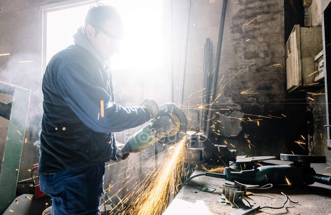 Man works with grinder cutting metal. — Stock Photo