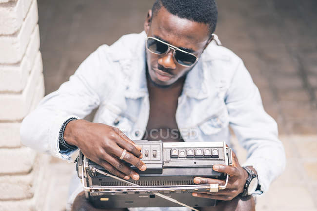 Ориентированный молодой человек, сидящий с винтажным радиоприбором — стоковое фото