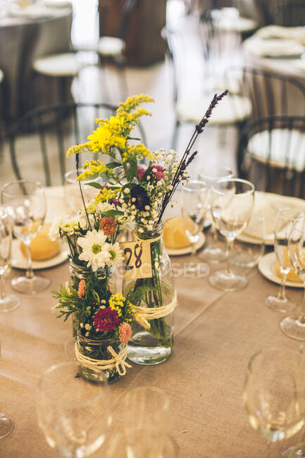 Яркие красивые ржавые цветы в бутылке на подаваемом банкетном столе. — стоковое фото