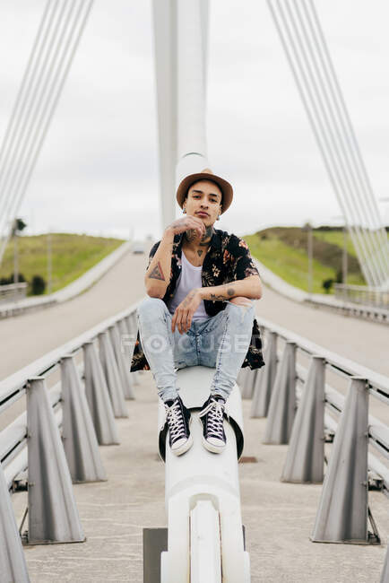 Hipster assis sur la rampe du pont — Photo de stock