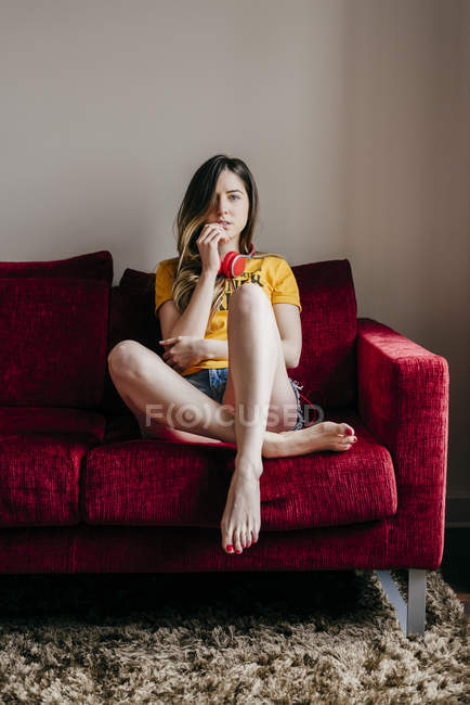 Женщина в наушниках сидит на диване — стоковое фото