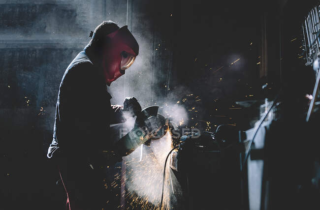 Mann arbeitet mit Schleifer, der Metall schneidet. — Stockfoto