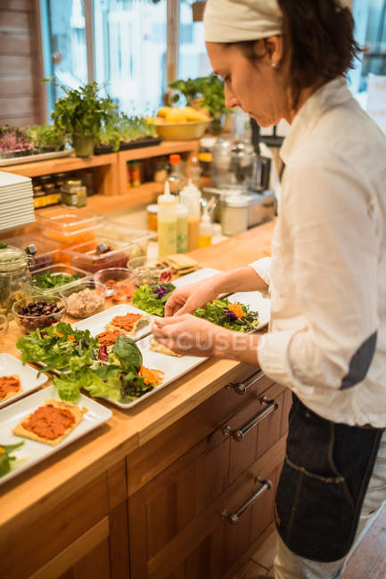 Mujer sirviendo platos con aperitivos veganos - foto de stock
