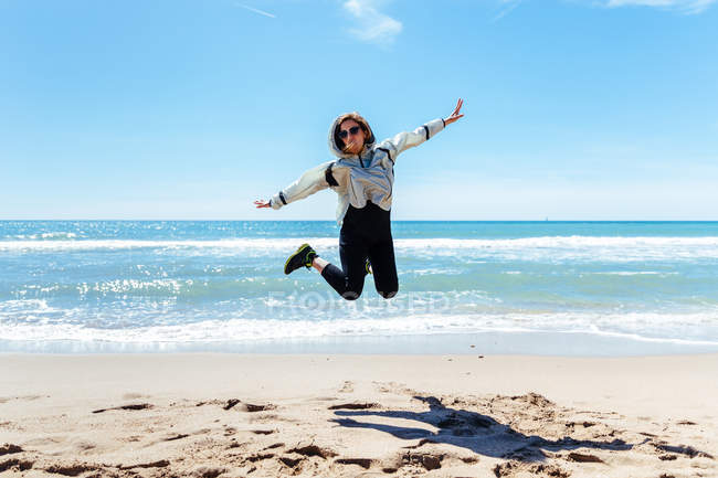 Женщина прыгает по песчаному пляжу — стоковое фото