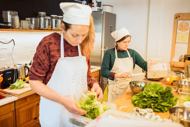 Women working with lettuce on kitchen — Stock Photo