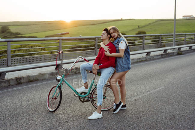Couple standing on bridge with vintage bicycle — Stock Photo