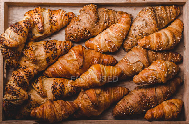 Mix of golden croissants in wooden tray — Stock Photo
