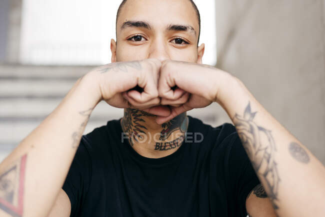 Hipster cubriendo la cara con manos tatuadas - foto de stock