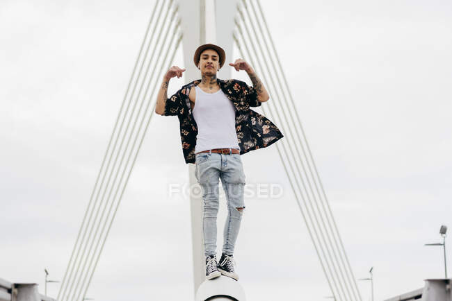 Hipster standing on railing of bridge — Stock Photo