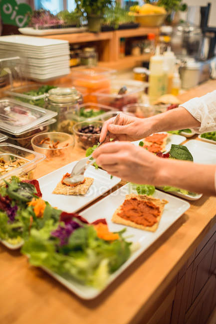 Mãos que servem pratos com lanches vegan — Fotografia de Stock