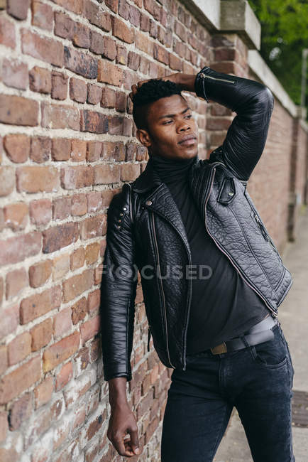 Homme noir appuyé sur le mur de briques — Photo de stock