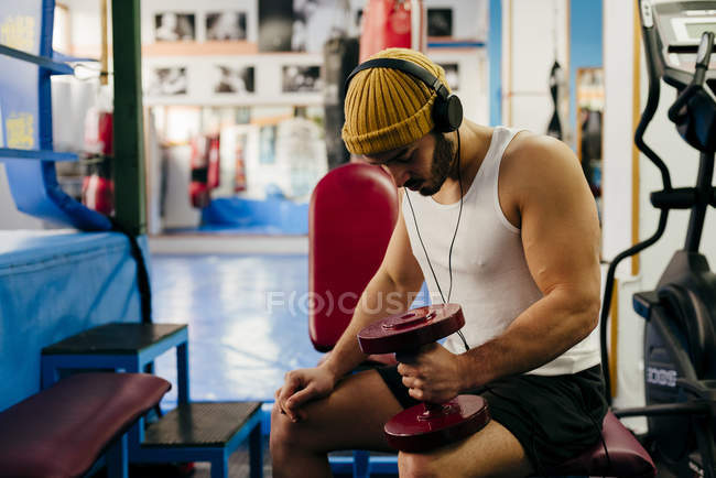 Мужчина тренируется с гантелями в тренажерном зале — стоковое фото