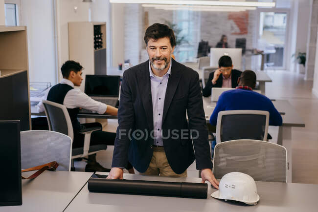 Красивый взрослый мужчина сидит на столе в офисе — стоковое фото