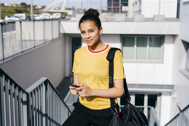 Woman with smartphone walking upstairs — Stock Photo