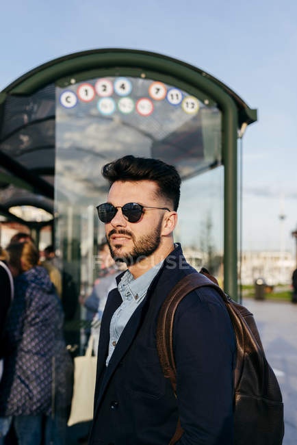 Mann mit Rucksack steht am Busbahnhof — Stockfoto