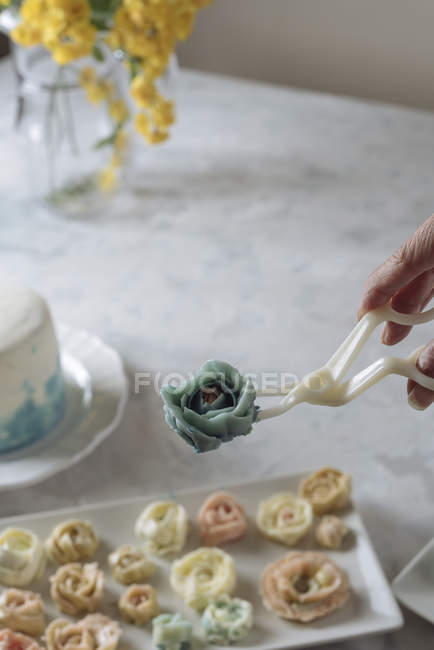 Hand holding buttercream flower — Stock Photo