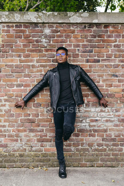 Homme posant contre un mur de briques — Photo de stock