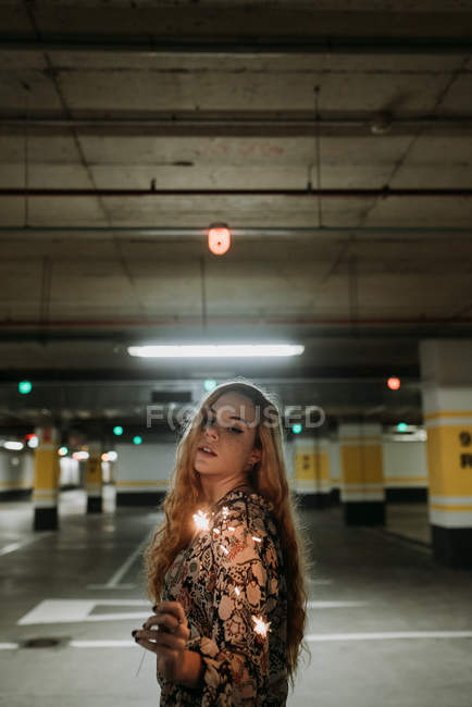 Junge Frau steht mit Wunderkerze auf Parkplatz — Stockfoto