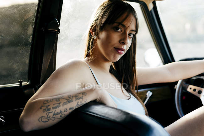 Morena mujer sentado en coche - foto de stock