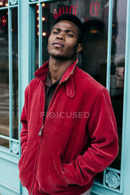 Homem de casaco vermelho em pé contra café — Fotografia de Stock