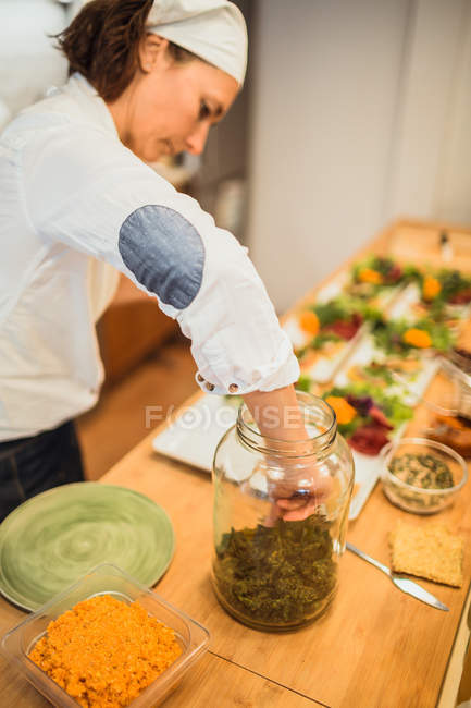 Woman taking spices from jar — Stock Photo