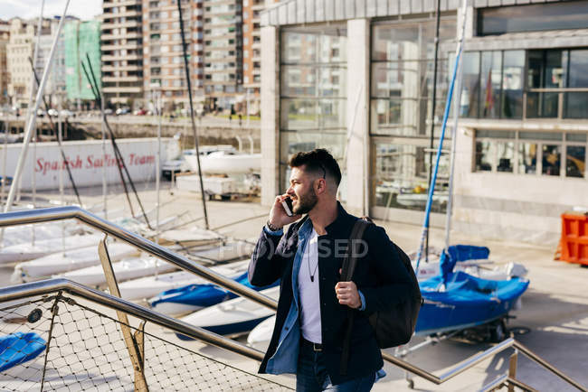 Hombre con mochila hablando en smartphone - foto de stock