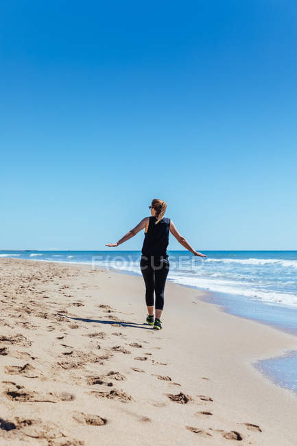 Frau bereitet sich auf Lauf am Sandstrand vor — Stockfoto